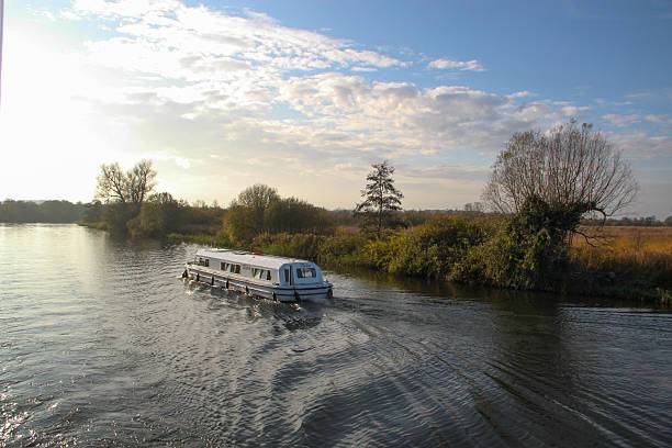 A group of friends enjoying a sunny day on a boat, surrounded by the scenic views of the Norfolk Broads