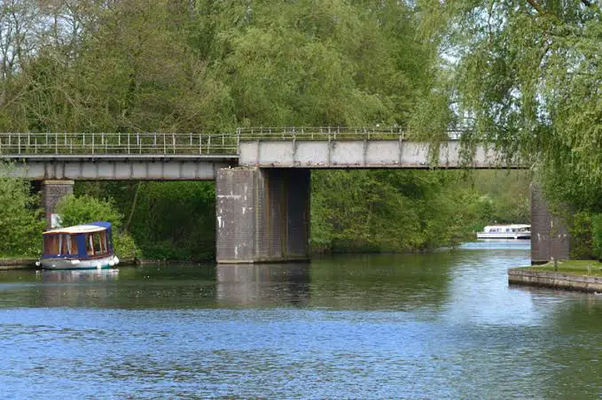 Image of the Wroxham Rail Bridge spanning over the tranquil waters of the River Bure in the Norfolk Broads at Wroxham. The bridge stands tall with its arched structure, overlooking the picturesque surroundings of this renowned Norfolk Broads destination.